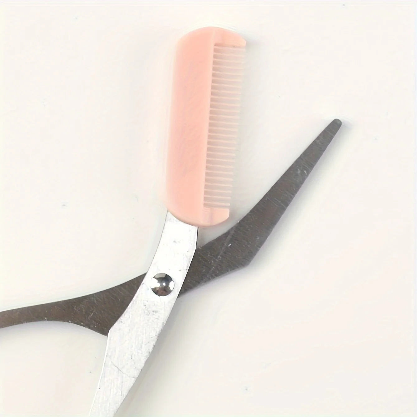 Pink eyebrow trimming scissors with built-in comb